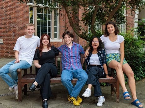 Group photo of the 2024/25 officer trustee team sitting on a bench outside in Beit Quad.