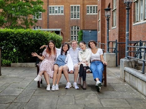 Group photo of the 2023/24 officer trustee team sitting on a bench outside in Beit Quad.