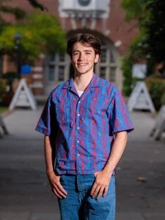 Headshot of Nico in Beit Quad, he is wearing a blue and pink patterned shirt and jeans